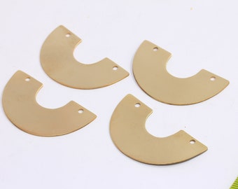 Puede incluir: Cuatro formas de metal de color dorado en forma de semicírculo con dos agujeros cada una. Las formas están dispuestas en forma de semicírculo sobre una superficie blanca.