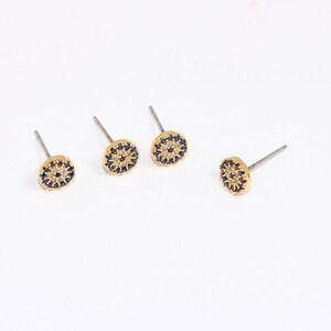 May include: Three pairs of gold stud earrings with a blue and white eye design.
