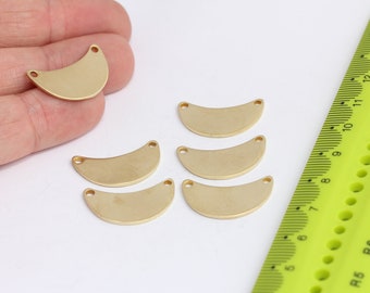 Puede incluir: Seis formas de media luna de metal de color dorado con dos agujeros en la parte superior. Las medias lunas están dispuestas en dos filas de tres. Una regla es visible en el fondo.