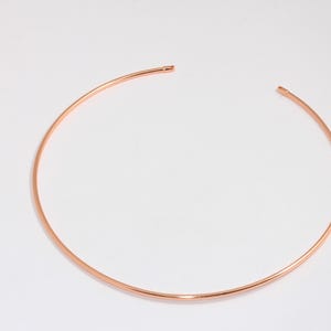 May include: A simple rose gold choker necklace. The necklace is a thin, continuous circle of metal.