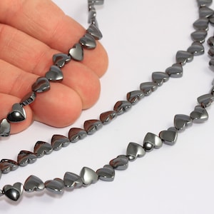 May include: A strand of black heart-shaped beads. The beads are made of hematite and are strung on a clear elastic cord.