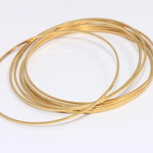 Può includere: Un set di anelli in metallo color oro, impilati e sovrapposti. Gli anelli sono lisci e lucidi.