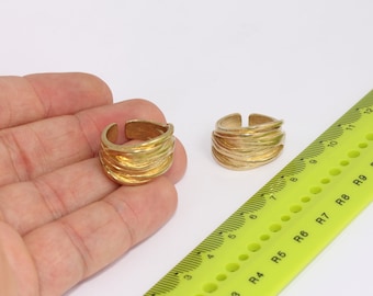 May include: Two gold-toned rings with a textured, wavy design. The rings are shown on a hand and next to a ruler.
