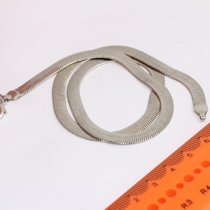 Op de afbeelding: Een zilveren slangenketting met een karabijn sluiting. De ketting is ongeveer 50 cm lang.