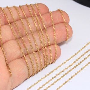 Peut inclure: Gros plan sur plusieurs brins de chaîne dorée, probablement pour la fabrication de bijoux. La chaîne est délicate et a une texture de corde.