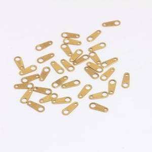 Könnte beinhalten: Ein Haufen kleiner, goldfarbener Metall-Sprünge. Die Ringe sind oval geformt mit einer kleinen Öffnung an jeder Seite.