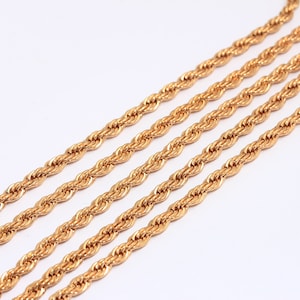 Puede incluir: Cuatro hebras de cadena de cuerda dorada, dispuestas en líneas paralelas sobre un fondo blanco.