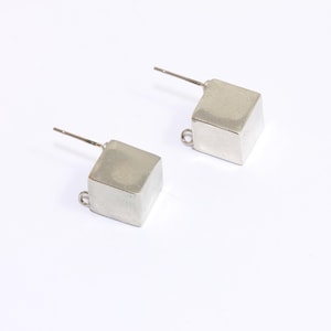 May include: A pair of silver cube earrings with a post and a small loop on the back.