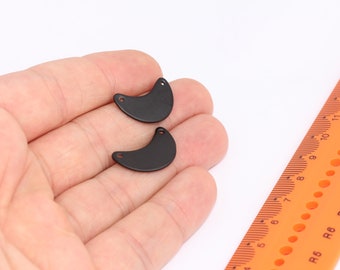 Könnte beinhalten: Zwei schwarze Halbmondformen aus Metall mit einem Loch oben. Die Formen haben einen Durchmesser von etwa 2,5 cm.