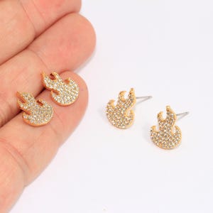 Puede incluir: Un par de pendientes de oro en forma de llama con detalles de cristal transparente.