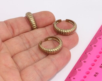 May include: Three gold-toned metal rings with a ridged design. The rings are shown on a hand against a white background.
