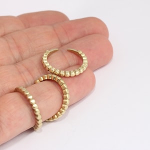 Puede incluir: Tres anillos dorados con un diseño de cuentas. Los anillos están apilados uno encima del otro.