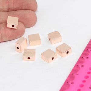 Peut inclure: Six perles carrées en or rose avec un trou au centre. Les perles mesurent environ 1,2 cm de diamètre.