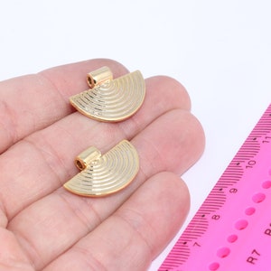 Puede incluir: Dos colgantes de metal de media luna de color dorado con un diseño texturizado de círculos concéntricos. Los colgantes tienen un bucle en la parte superior para sujetarlos a una cadena o cordón.