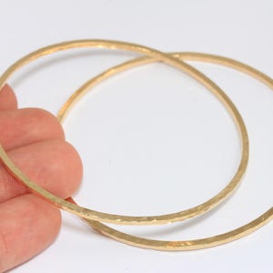 Puede incluir: Dos pulseras de brazalete doradas con textura martillada.