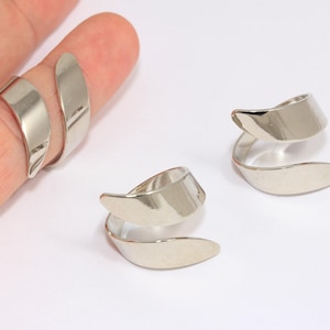 May include: Two silver rings with a unique twisted design. The rings are made of metal and have a smooth, polished finish.