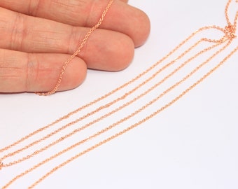 May include: Five strands of rose gold chain, laid out in a straight line on a white surface.