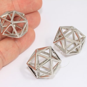 May include: Three silver geometric shaped beads. Each bead is a hollow, open-frame design with triangular and quadrilateral facets. The beads are displayed against a white background.