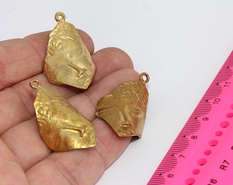 Può includere: Tre ciondoli in metallo color oro con disegni intricati. Ogni ciondolo ha un anello nella parte superiore per attaccarlo a una catena o un cordino.