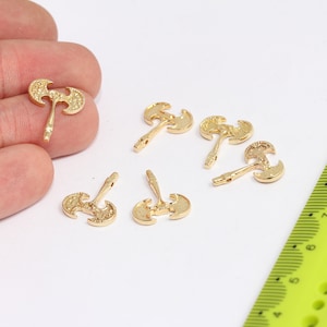 May include: Six gold-colored axe charms with a textured surface. The charms are small and have a loop at the top for attaching to jewelry or other crafts.
