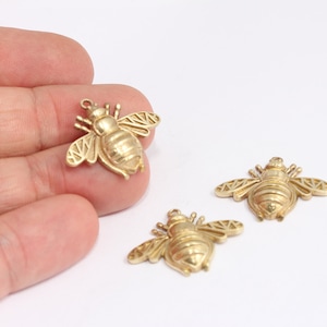 Può includere: Tre ciondoli a forma di ape dorati con ali e corpi dettagliati. I ciondoli sono in metallo e hanno una finitura lucida.