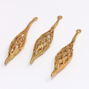 May include: Three gold-colored metal pendant charms shaped like a teardrop with a delicate, openwork design.