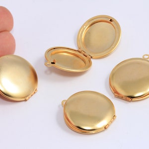 Puede incluir: Cuatro colgantes de medallón de metal dorado con una abertura con bisagras. Cada medallón tiene una superficie lisa y redonda y un pequeño bucle en la parte superior para sujetar una cadena.