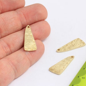 Peut inclure: Trois pendentifs en métal de forme triangulaire de couleur dorée avec une texture martelée. Chaque pendentif a un petit trou en haut pour attacher une ficelle ou une chaîne.
