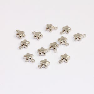 May include: A group of silver star-shaped charms with a loop for attaching to jewellery or other crafts.