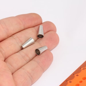 Puede incluir: Tres tapones de extremo de cono de metal plateado para cables o cordones.