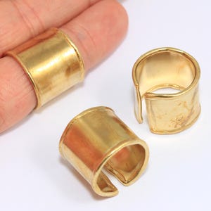 Könnte beinhalten: Drei goldfarbene Metallringe, zwei sind offen und einer ist geschlossen. Die Ringe sind dick und haben eine glatte, polierte Oberfläche.