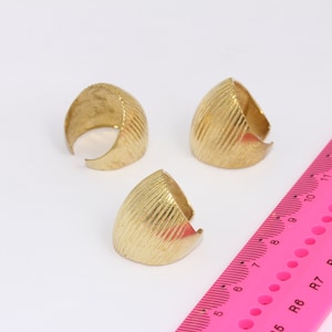 May include: Three gold-colored metal rings with a textured surface. The rings are half-circles and are about 1 inch in diameter.