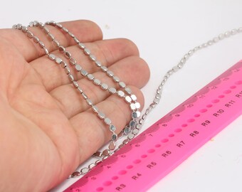 May include: A silver chain with oval-shaped links, measured against a pink ruler marked with numbers and letters. The chain is approximately 13 inches long.