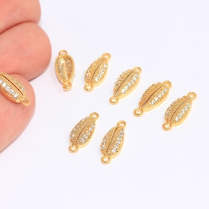 May include: Eight gold-tone shell-shaped connector charms with clear crystal accents. Each charm has two jump rings for attaching to jewelry.