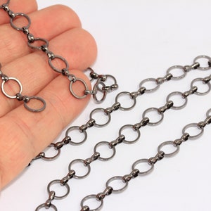 Pode incluir: Close-up de uma corrente preta com elos redondos. A corrente é feita de metal e tem um acabamento fosco.