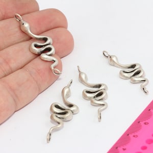 Puede incluir: Cuatro abalorios de serpiente plateados con un bucle en la parte superior para sujetarlos a joyas. Los abalorios miden aproximadamente 5 cm de largo.