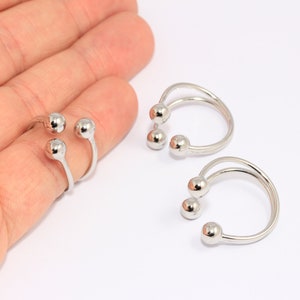 Op de afbeelding: Twee zilveren ringen met elk drie ronde kralen. De ringen zijn open en kunnen worden aangepast aan verschillende vingermaten.