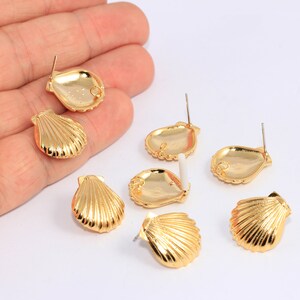 May include: Six gold-tone seashell shaped stud earrings. The earrings are all the same design, but are in different positions on a hand.