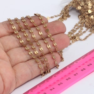 May include: Gold chain with small round links. The chain is approximately 12 inches long and is shown on a hand.