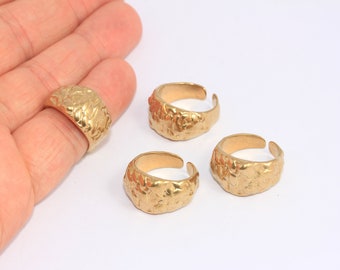 May include: Four gold-toned rings with a textured, hammered finish. The rings are all different sizes and are stacked on top of each other.