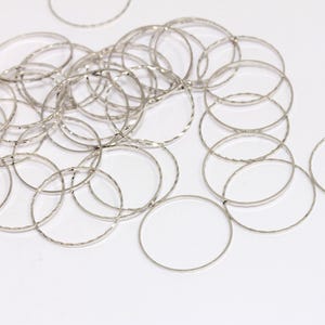 Könnte beinhalten: Ein Stapel silberfarbener Metall-Sprünge. Die Ringe sind alle gleich groß und haben eine strukturierte Oberfläche.