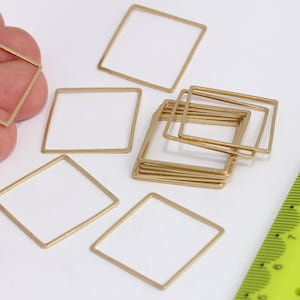 May include: A group of 10 gold-coloured metal square frames, some stacked on top of each other. A ruler is in the background.