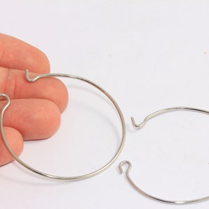 Könnte beinhalten: Zwei silberne Metallreifen mit Hakenverschluss. Die Reifen haben einen Durchmesser von etwa 5 cm.