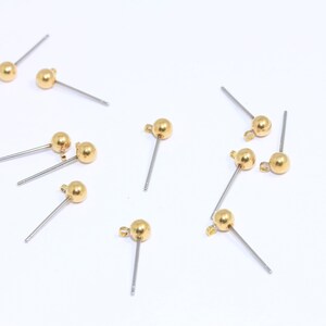 Peut inclure: Dix fermoirs d'oreille dorés avec une petite boule à l'extrémité de chaque épingle. Les épingles sont droites et ont une boucle en haut.