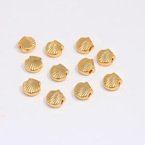 Peut inclure: Douze perles dorées en forme de coquillage. Les perles sont lisses et ont une finition brillante.