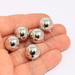 May include: Five silver ball earrings with posts. The earrings are round and shiny.