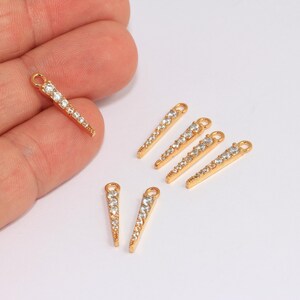 Puede incluir: Encantos de metal dorado con diamantes de imitación transparentes en forma de punta. Los encantos tienen un bucle en la parte superior para sujetar a las joyas.