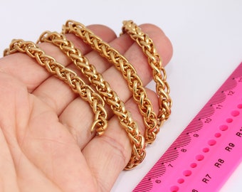 Puede incluir: Tres cadenas de oro de diferentes longitudes, tejidas en un patrón de cuerda, se colocan sobre una mano. Una regla rosa con marcas negras está en el fondo.