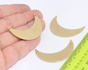 Puede incluir: Tres formas de media luna de metal de color dorado con agujeros en la parte superior. Las lunas tienen un diámetro de aproximadamente 5 cm.