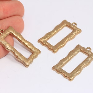 Può includere: Tre cornici rettangolari in metallo dorato con superficie testurizzata. Ogni cornice ha un piccolo anello nella parte superiore per appenderla.